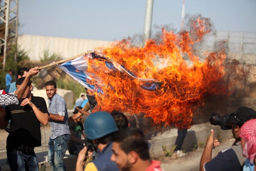 Palestijnse demonstranten verbranden een vlag van Israël.