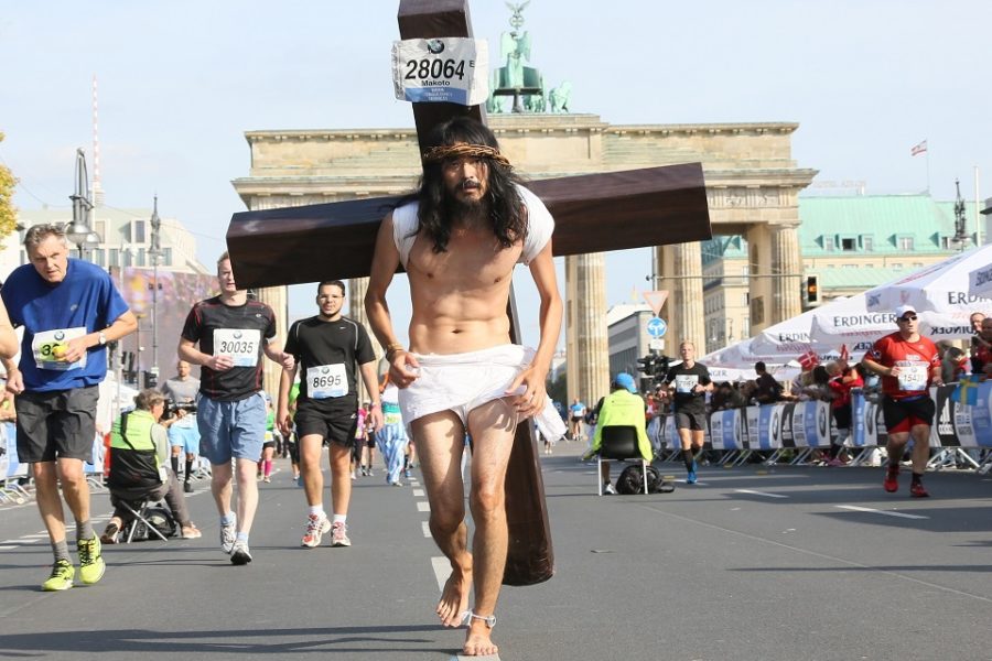 Met een kruis op de rug en blootsvoets loopt een deelnemer, verkleed als Jezus
de marathon van Berlijn.