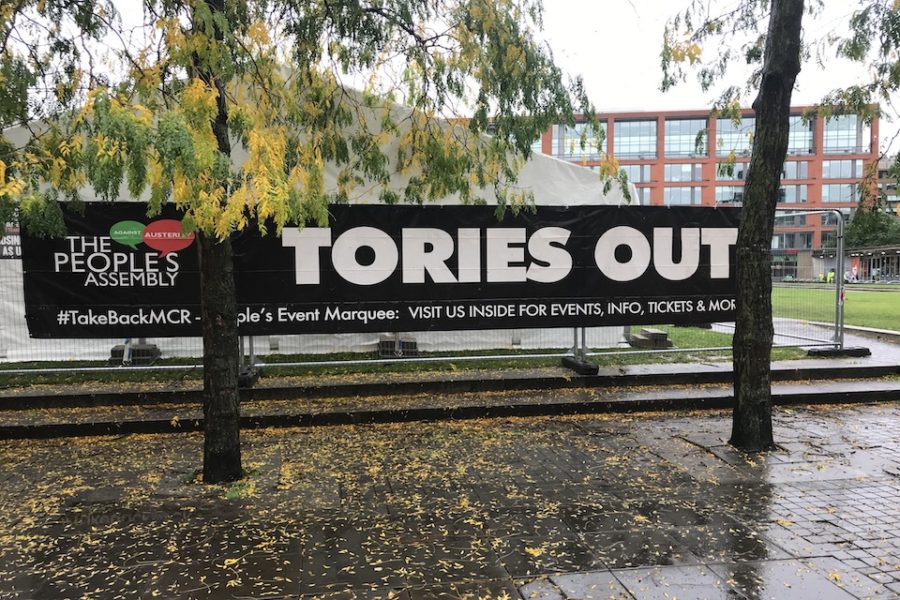 ‘Tories Out!’ dicteert een spandoek terwijl ik een groot plein oversteek in het
natte Manchester.
