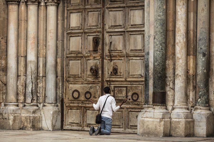 Een man bidt voor de gesloten poort van de Kerk van het Heilig Graf in
Jeruzalem. De kerk was tijdens de Paasdagen gesloten als gevolg van de
maatregelen tegen de verspreiding van het coronavirus.