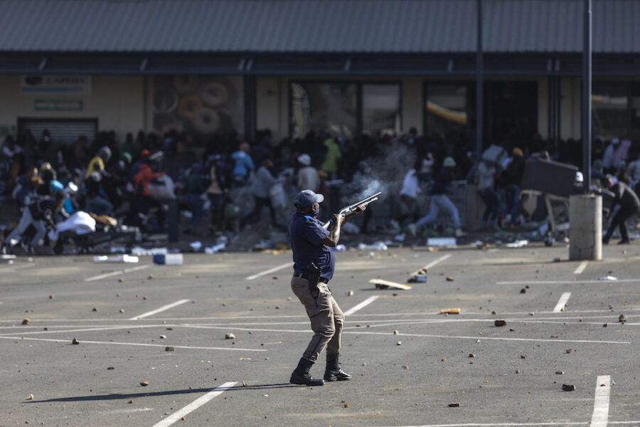 Een SAPS agent schiet met rubber kogels naar plunderaars in Soweto.