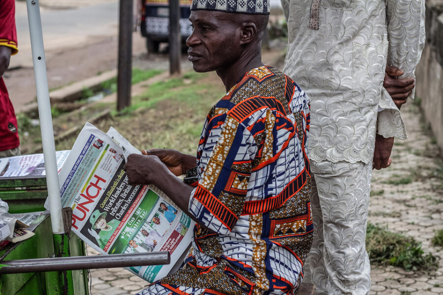 Een krantenverkoper in de voormalige Britse kolonie Nigeria leest het nieuws
over Queen Elisabeth II