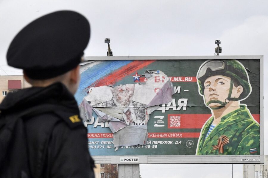 Een jonge kadet kijkt naar een reclamebord van het Russische leger.